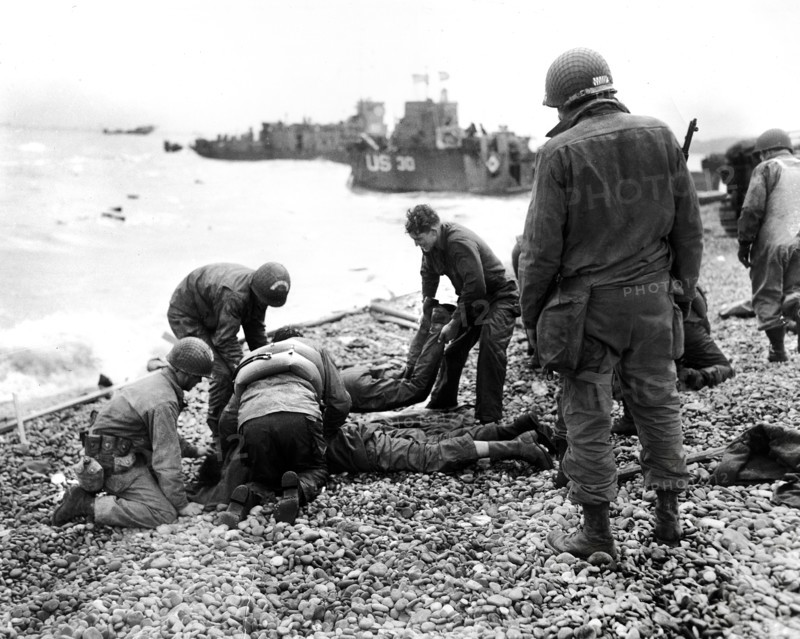 American soldiers applying artificial respiration on two other soldiers who reached the north coast of France in rubber life raft after their landing craft was sunk by enemy action while several hundred yards from shore, near Cherbourg, Normandy, France, Weintraub, U.S. Army Signal Corps, June 6, 1944