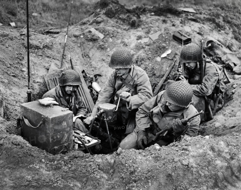 Members of shore fire control party set up "shop" in old shell hole and immediately proceed to direct fire of Naval guns against targets on beach, Normandy, France, U.S. Army Signal Corps, June 10, 1944