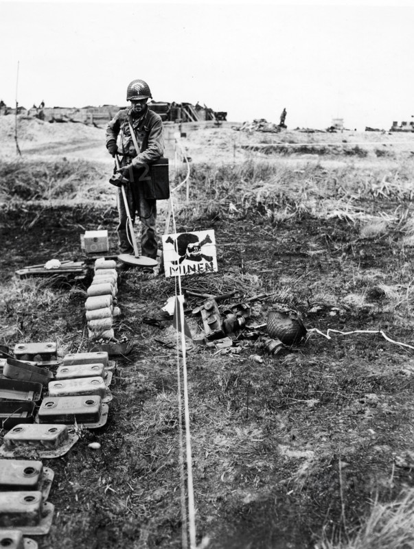 1st Lieutenant Merle Kirstein, Des Moines, Iowa, going through German-marked minefield with detector to pick out any explosive mines that might be left, Normandy, France, U.S. Army Signal Corps, June 13, 1944