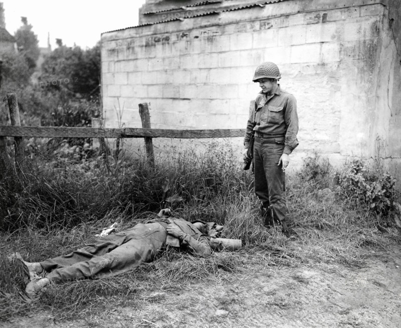 U.S. Sergeant Joseph C. Self of Harriman, Tennessee, looking over dead German sniper, Omaha Beachhead, near Vierville-sur-Mer, Normandy, France, Todd, U.S. Army Signal Corps, June 10, 1944