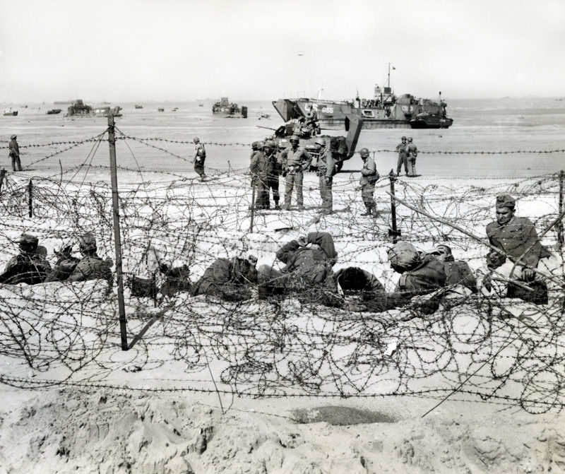 German prisoners resting in barb-wired enclosure after being interrogated by American soldiers, Utah Beach, La Madeleine, Normandy, France, Petrony, U.S. Army Signal Corps, June 6, 1944
