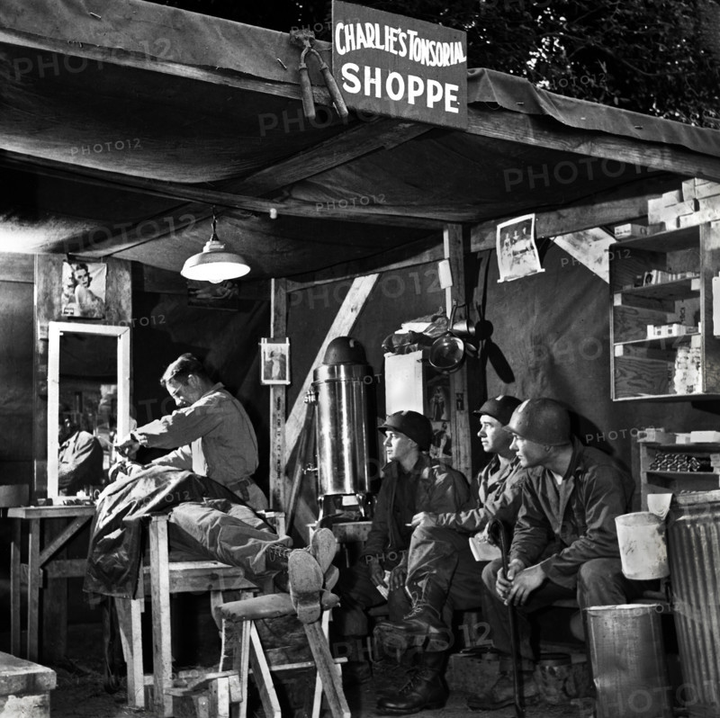 American soldiers wait their turn at Charlie's Tonsorial Shoppe, Normandy, France, U.S. Army Signal Corps, 1944