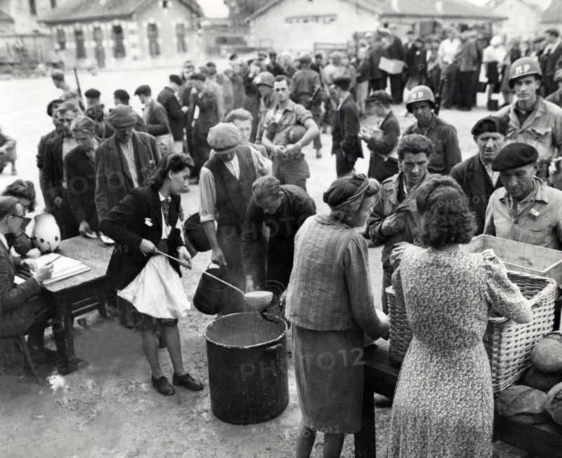 Homeless people who were being cared for by members of civil affairs unit queue up for noonday meal at displaced persons center where they were staying, Verdun, France, U.S. Army Signal Corps, September 16, 1944