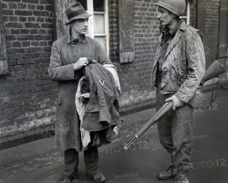U.S. Staff Sargeant Martin M. Gruenspecht of New York City, New York, member of the 1st Infantry Division, U.S. First Army, being informed by German prisoner that he took off his uniform because he was afraid of being shot by American forces, Bliesheim, North Rhine-Westphalia, Germany, U.S. Army Signal Corps, March 4, 1945