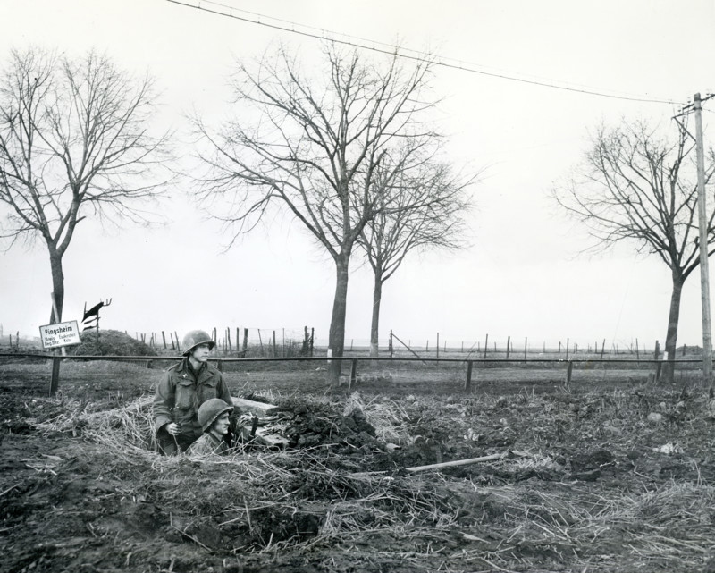 James E.J. Jentry of Bristol, Tennessee and Pfc. John W. Harris of Portland, Oregon, infantrymen of 1st Infantry Division, U.S. First Army, on alert in their foxhole, Pingsheim, North Rhine-Westphalia, Germany, U.S. Army Signal Corps, March 2, 1945