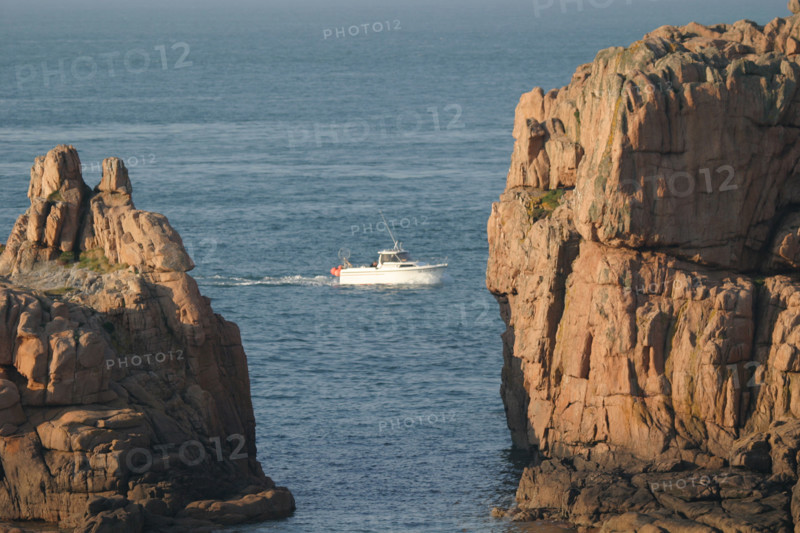 France, Bretagne, Cotes d'Armor, cote de granit rose, ploumanach, petit bateau passant entre deux rochers,