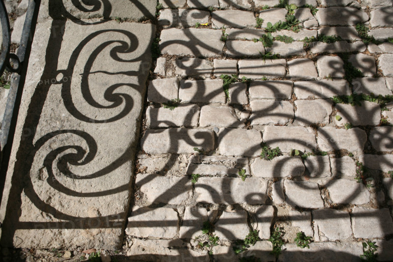 France, languedoc roussillon, gard, uzes, ombre de ferronneries d'un balcon sur le sol, paves, vieille ville, habitat traditionnel,