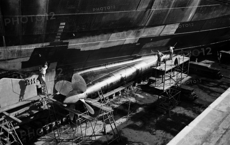 Men clean and paint the hull of a ship in the New Dry Dock, Tilbury Docks, Tilbury, c1945-c1965