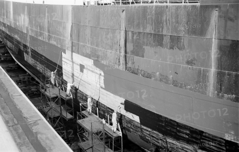 Men paint the hull of a ship in the New Dry Dock, Tilbury Docks, Tilbury, Essex, c1945-c1965