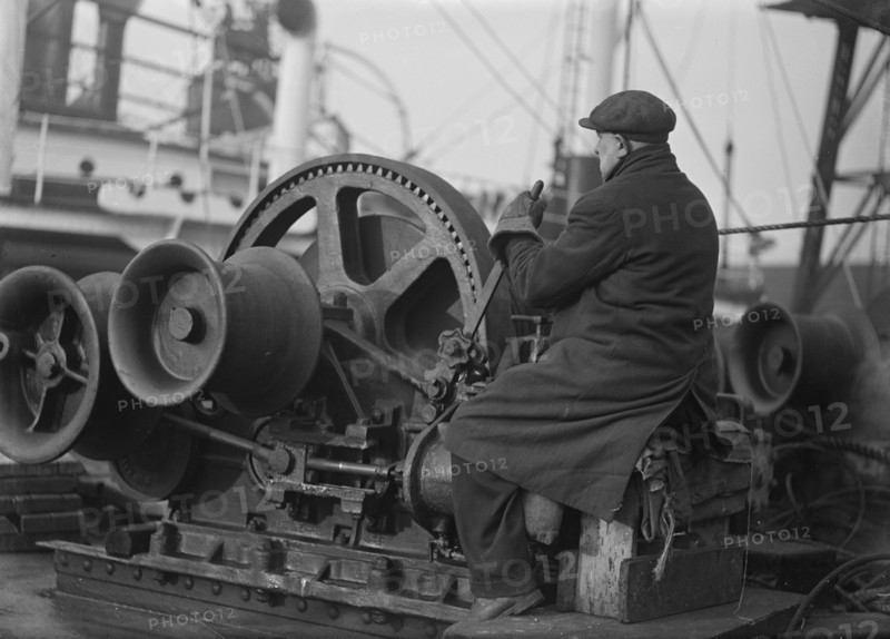 A docker operates a winching gear in London Docks, London, c1945-c1965