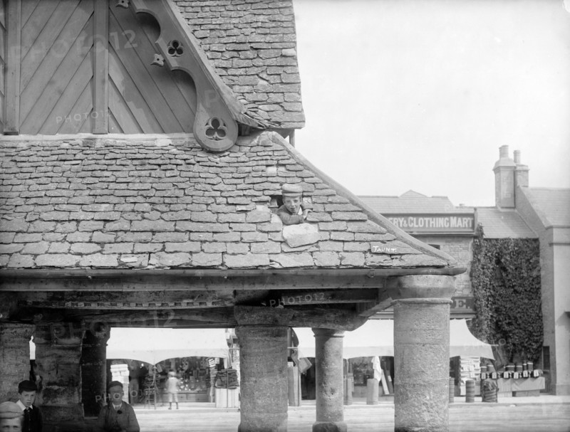 Boy poking his head through the roof of the 17th-century Buttercross, Witney, Oxon, c1860-c1922