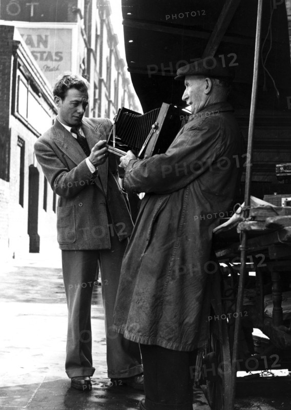 Man browsing a stall at Camden Town, 1950s. Artist: Henry Grant