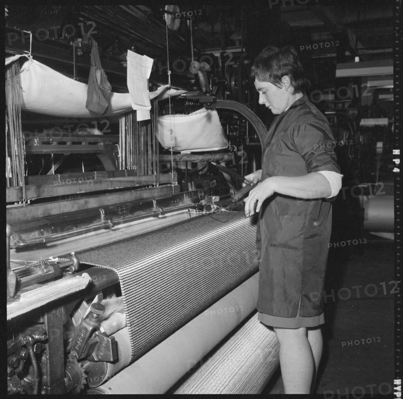 Weaver preparing a shuttle for use in a power loom, 1966-1974