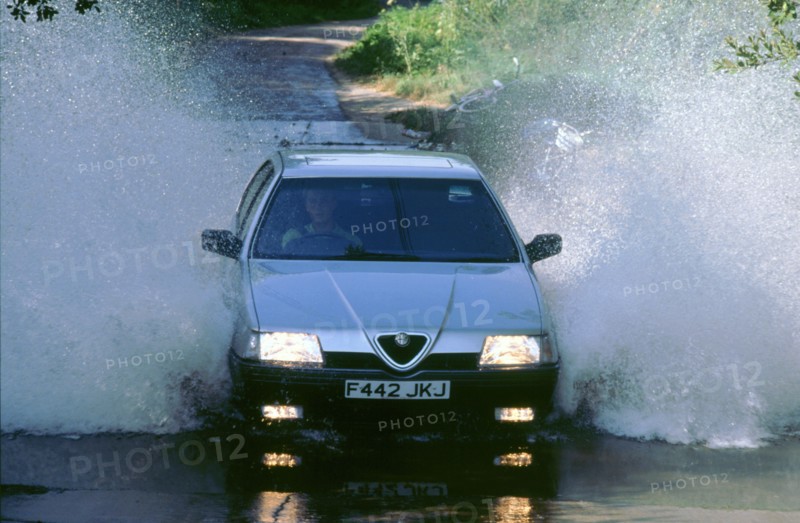 1989 Alfa Romeo 164 driving through a ford. Artist: Unknown.