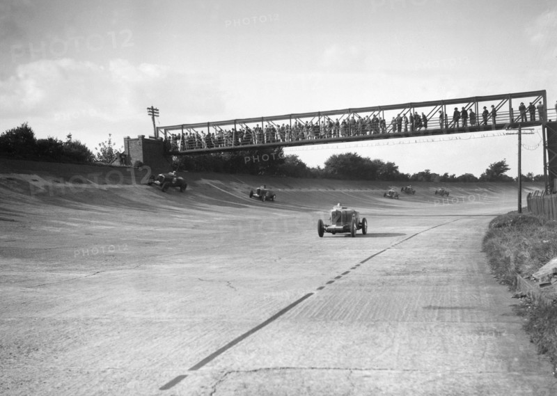 Cars racing on Byfleet Banking during the BRDC 500 Mile Race, Brooklands, 3 October 1931. Artist: Bill Brunell.
