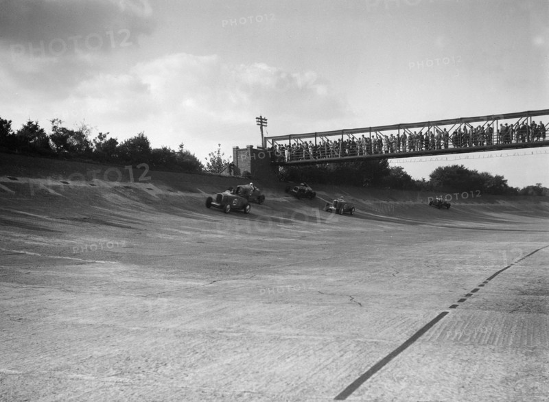 Cars racing on Byfleet Banking during the BRDC 500 Mile Race, Brooklands, 3 October 1931. Artist: Bill Brunell.