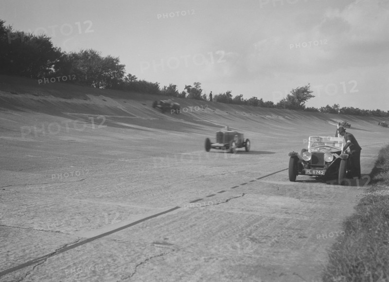 Cars racing on Byfleet Banking during the BRDC 500 Mile Race, Brooklands, 3 October 1931. Artist: Bill Brunell.