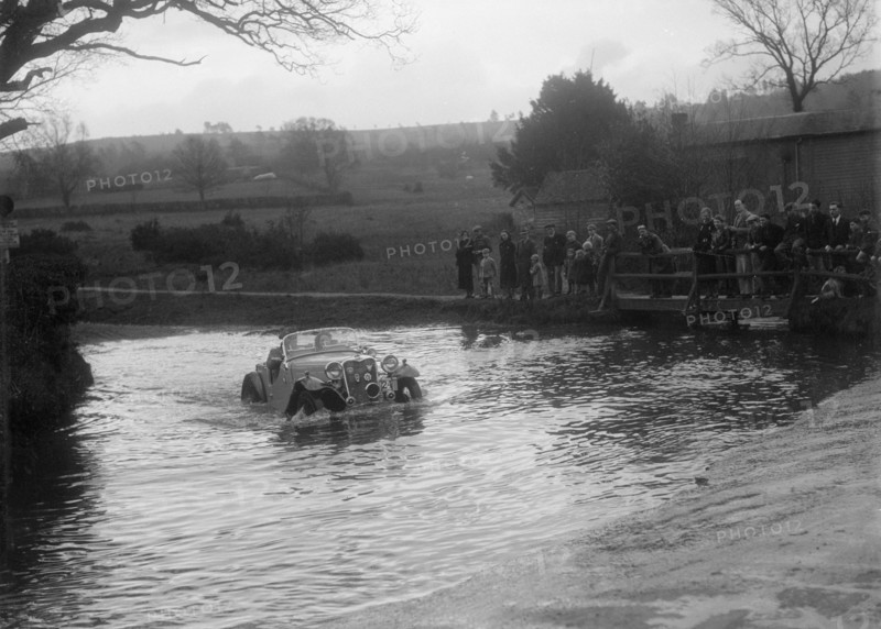 972 cc Singer Le Mans driving through a ford during a motoring trial, 1936. Artist: Bill Brunell.