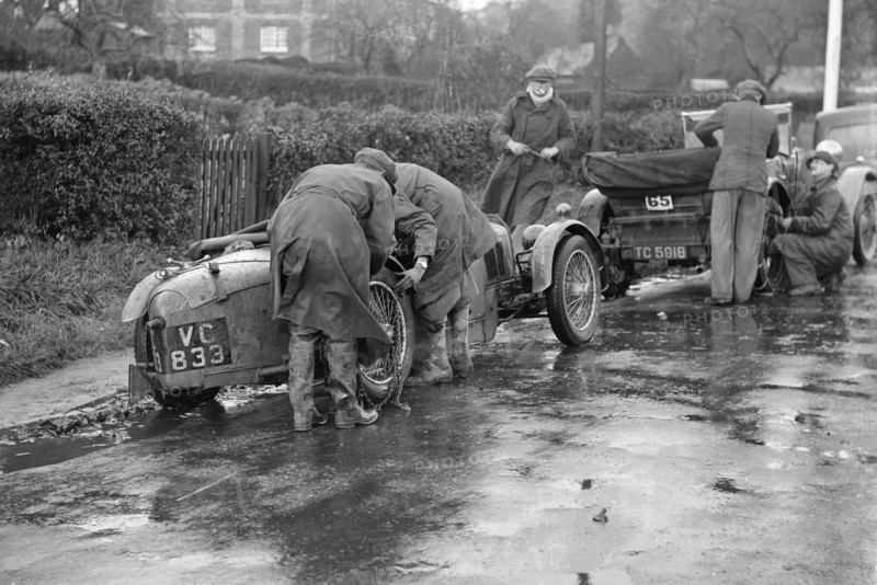 Attaching snow chains to JE Lancaster's Riley Brooklands during the Inter-Varsity Trial, 1930. Artist: Bill Brunell.