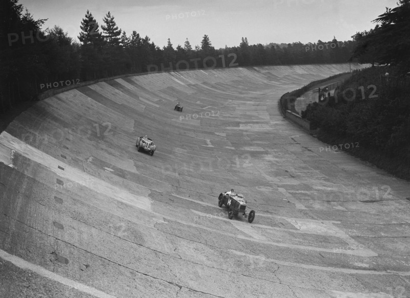 Frazer-Nash and Frazer-Nash BMW racing on the banking at Brooklands, 1938 or 1939. Artist: Bill Brunell.