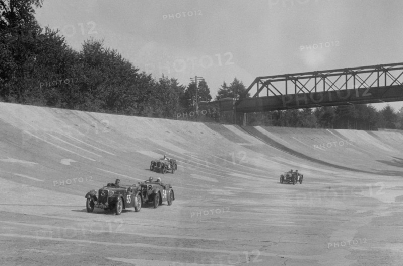 Singers of TW Fassett and Alf Langley and an MG racing at a MCC meeting, Brooklands, Surrey, 1933. Artist: Bill Brunell.