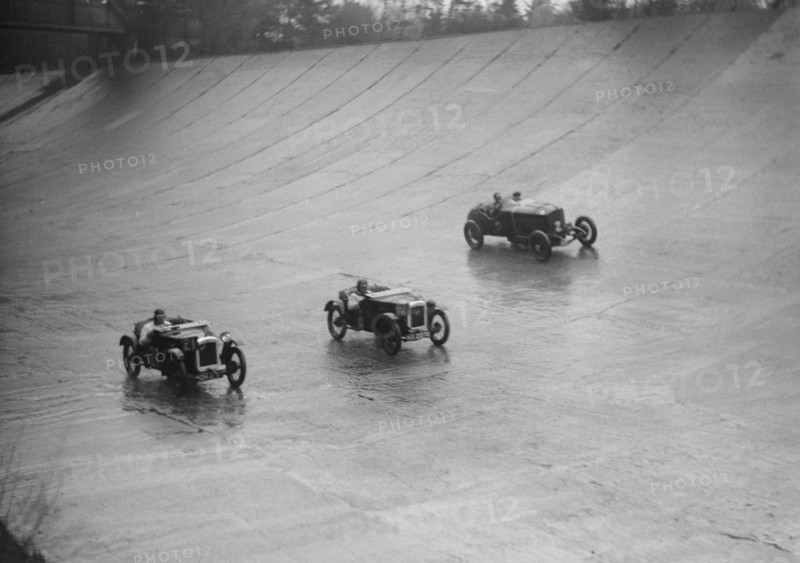 Two Austin 7s and an unidentified car racing at a BARC meeting, Brooklands, Surrey, 1931 Artist: Bill Brunell.