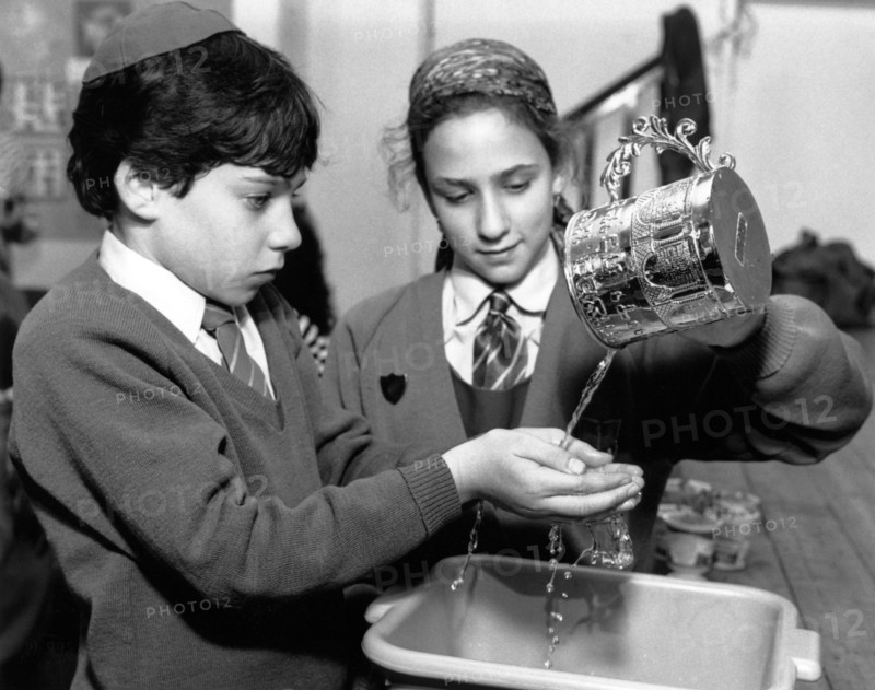 Jewish children performing ritual hand-washing, April 1991. Artist: Sidney Harris