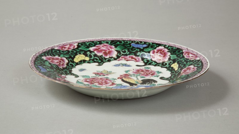 European copy of famille noire plate with cockerel looking at a butterfly, 20th century. Artist: Unknown.