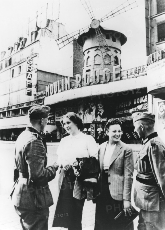 Des soldats allemands discutant avec des Françaises devant le Moulin Rouge, Paris occupé, juin 1940.