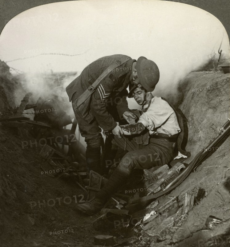 Soldier receiving first aid from a sergeant in a sap, Battle of Peronne, World War I, 1914-1918.Artist: Realistic Travels Publishers