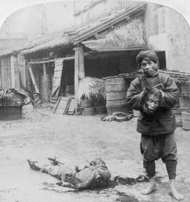 'The grim executioner taking the labled head to exhibit a warning', Canton, China, 1900.  Artist: Underwood & Underwood