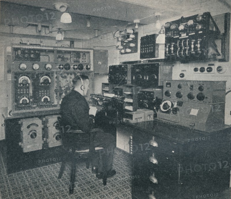 'A Marconi wireless operator receiving wireless messages as the Empress of Britain crosses the Atlan Artist: Unknown.