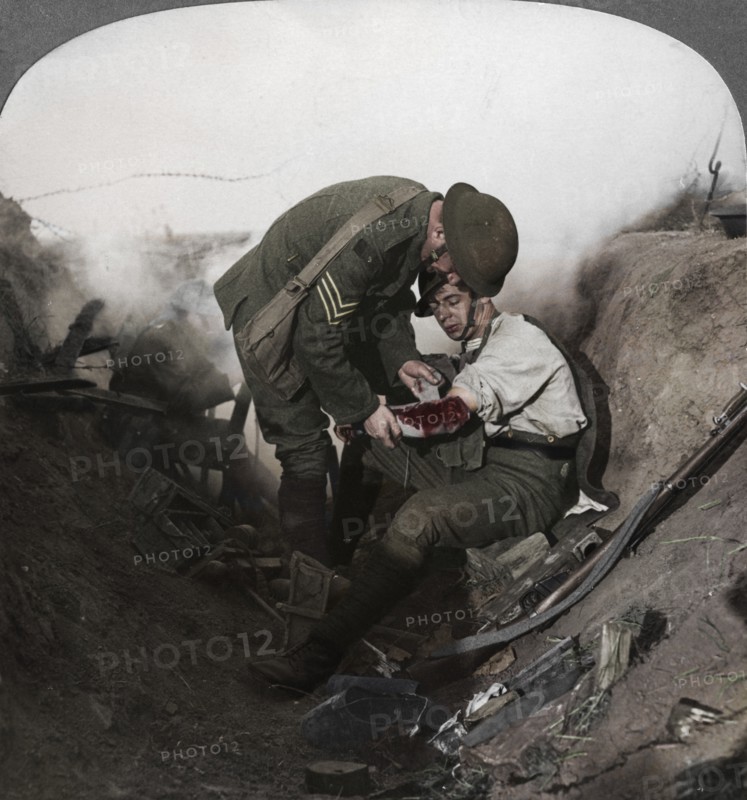 Soldier receiving first aid from a sergeant in a sap, Battle of Peronne, World War I, 1914-1918. Artist: Realistic Travels Publishers.