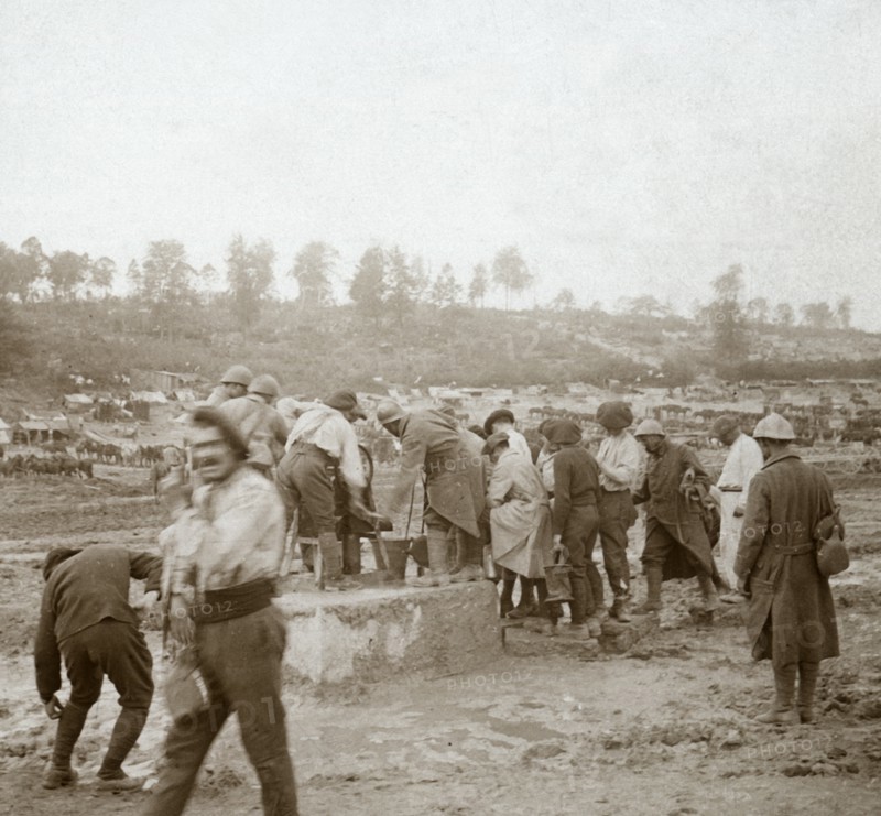 Soldiers queuing in the mud for water, Genicourt, northern France, c1914-c1918. Artist: Unknown.