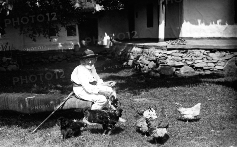 Old man feeding chickens, Bistrita Valley, Moldavia, north-east Romania, c1920-c1945. Artist: Adolph Chevalier