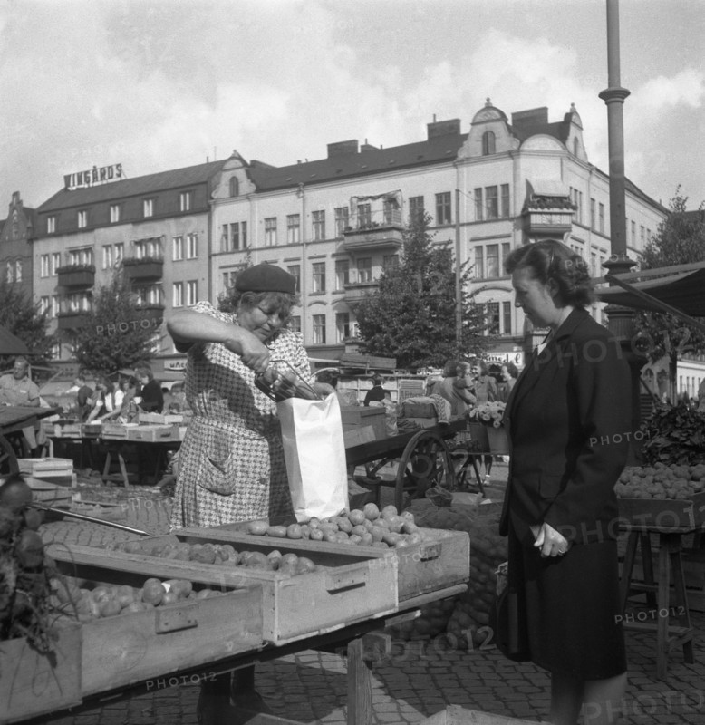 Woman buying potatoes from a fruit and vegetable stall in the market, Malmö, Sweden, 1947. Artist: Otto Ohm