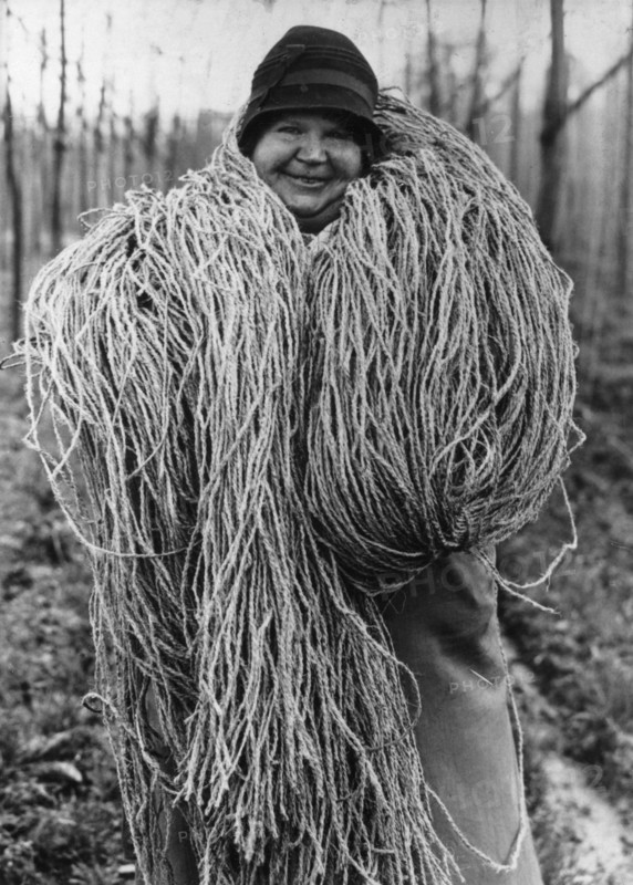 Woman carrying a large bundle of string or fibre, c1937. Artist: Unknown