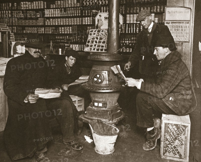 A group of men around a stove in a shop, USA, c1910. Artist: Unknown