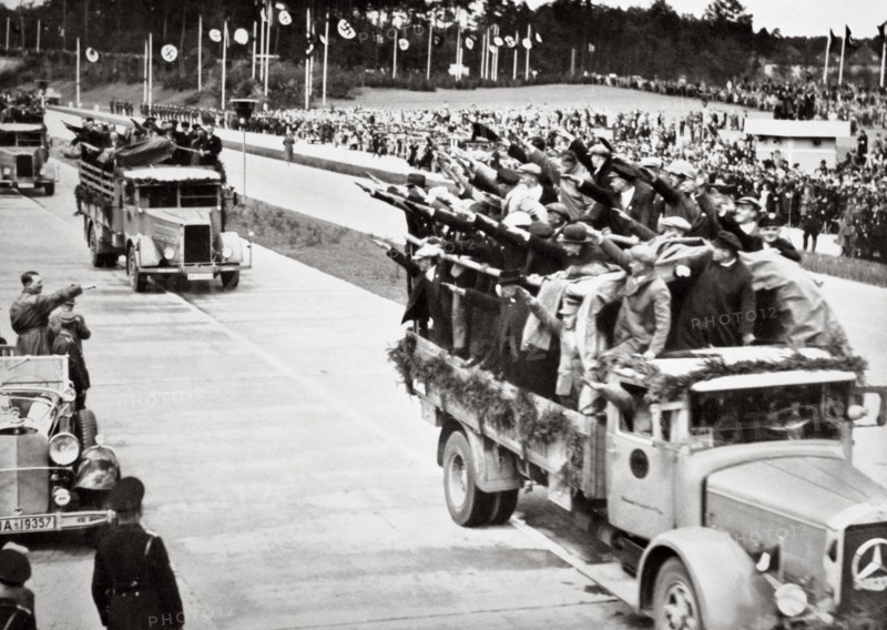 Labourers salute Hitler from packed trucks on a Nazi-built road, 1936. Artist: Unknown