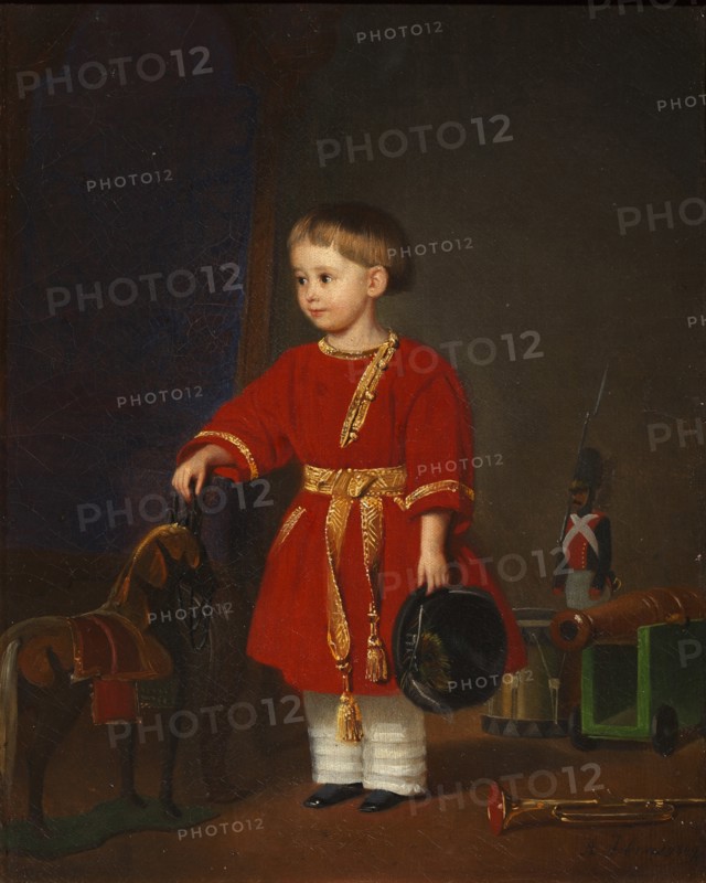 Portrait of a boy in a red dress with military toys.