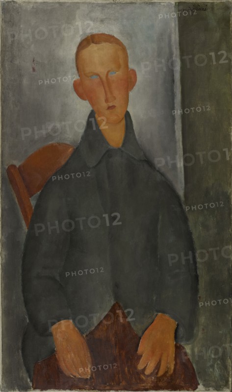Seated boy with red hair and grey jacket.