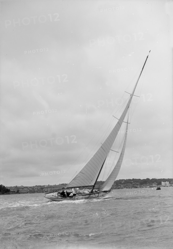 12 Metre class sailing yacht heeling over in windy conditions on upwind leg, 1938. Creator: Kirk & Sons of Cowes.