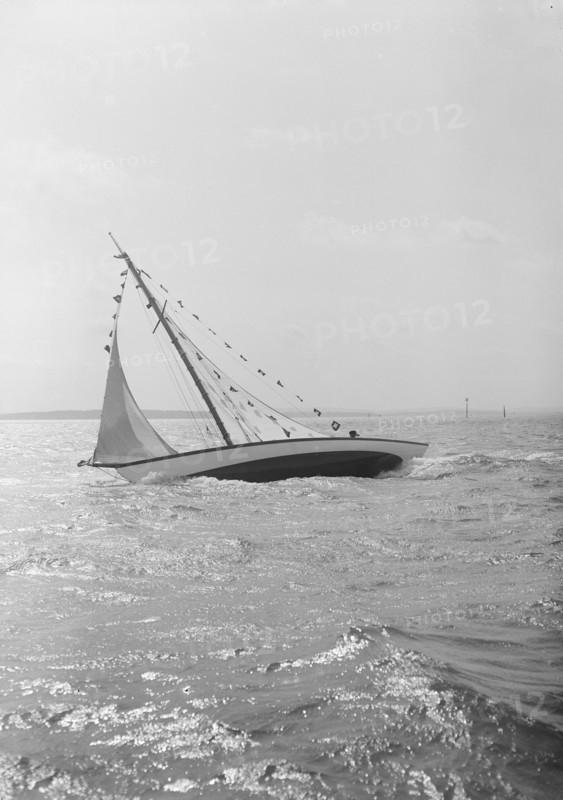 The 7 Metre 'Ginerva' (K7) under sail with prize flags, 1912. Creator: Kirk & Sons of Cowes.