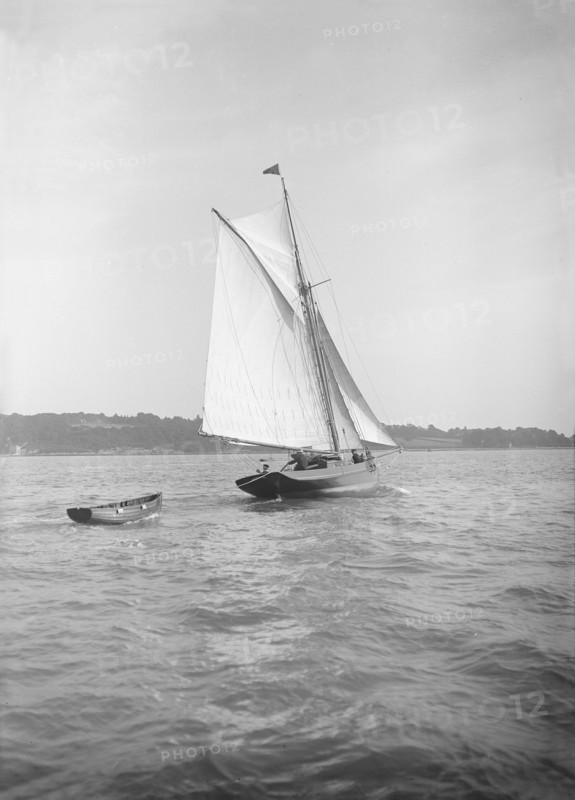 The cutter 'Citara' under sail and towing tender, 1911. Creator: Kirk & Sons of Cowes.