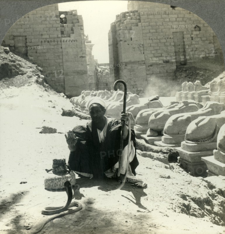 'An Egyptian Snake Charmer Piles His Trade Beside the Avenue of Sphinxes, Temple of Karnak, Thebes,  Creator: Unknown.