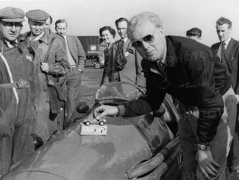 Mike Hawthorn admiring a toy model Ferrari on his racing Ferrari. Creator: Unknown.