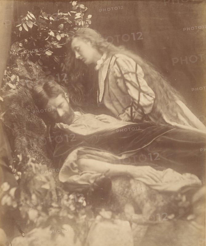 Gareth and Lynette, 1874. A bearded man (Andrew Hichens) poses as Gareth reclining with head cast down and eyes closed. A woman (May Prinsep Hichens), poses as Lynette, standing and leaning above him with unbound hair and her left hand resting on his chest. A photographic illustration to Alfred Tennyson's "Idylls of the King"; a series of narrative poems based on the legends of King Arthur.