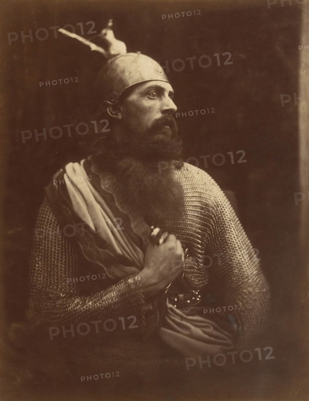 The Passing of King Arthur, 1874. A melodramatic depiction of Arthur?s death scene.  A bearded man (William Warder) in profile, wearing chainmail and an armour helmet with his right hand gripping a sword. A photographic illustration to Alfred Tennyson's "Idylls of the King"; a series of narrative poems based on the legends of King Arthur.