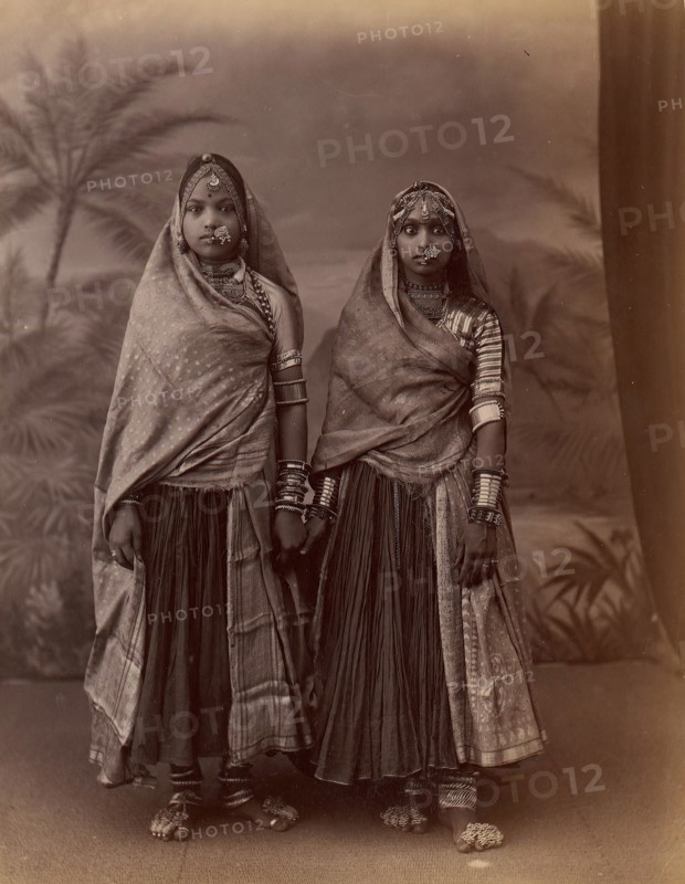 Two Hindu Women in Elaborate Jewelry, Before Studio Backdrop with Palm Trees, 1860s-70s.