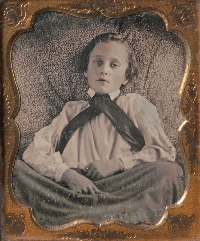 Boy Seated Cross-legged, Partially Covered by Blanket, Leaning Against Cushion, 1850s.